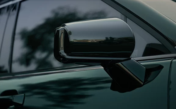 Close-up of the gloss black power-folding side mirror on a dark green Palisade