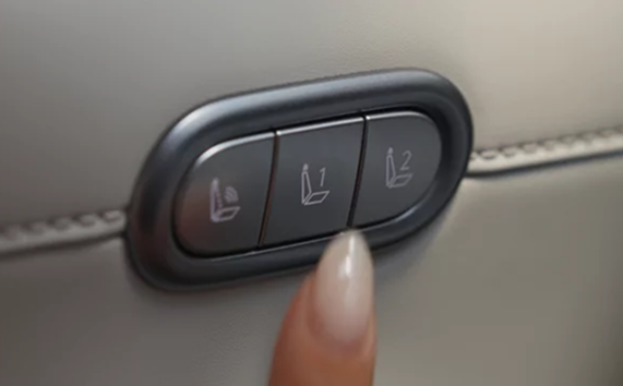 A finger pressing a driver seat memory button on the Palisade door panel