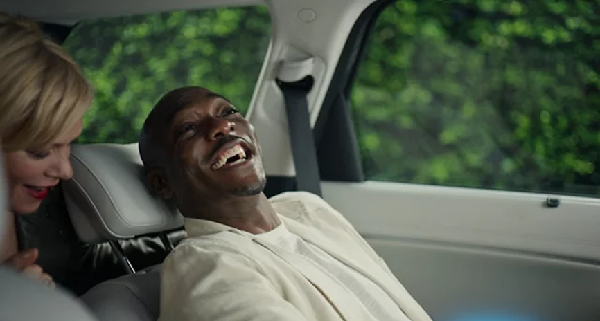 A man laughing while reclined in a Palisade relaxation seat beside a passenger