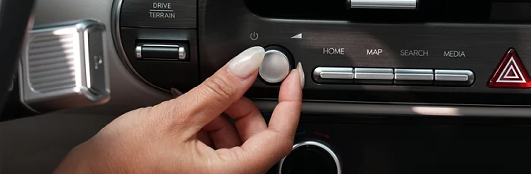 A hand turning the volume knob below the Palisade touchscreen controls