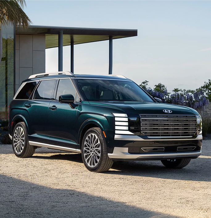A dark green Hyundai Palisade parked on gravel beside a modern carport