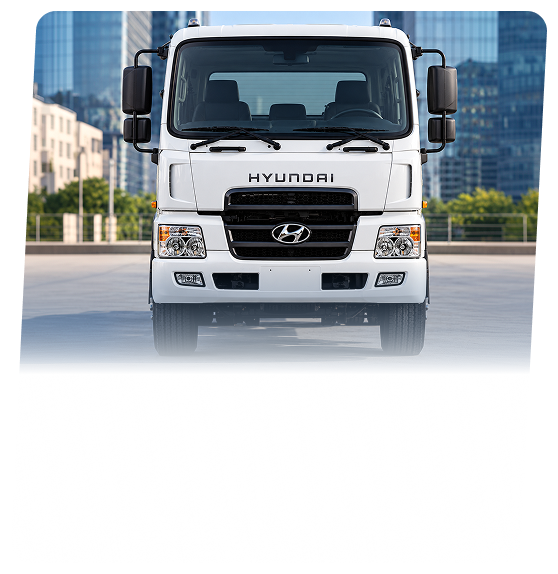 A white Hyundai commercial cab-over truck seen head-on on a city street