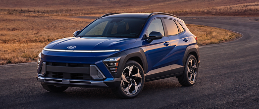 A blue Hyundai Kona crossover on a desert road at sunset