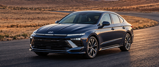 A dark blue Hyundai Sonata sedan on a desert road at sunset