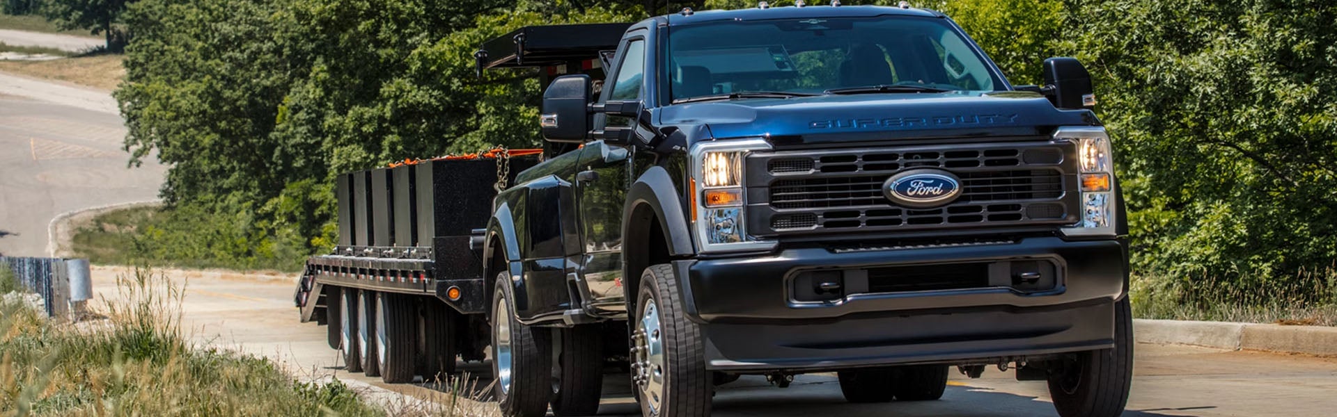 Ford Super Duty truck towing a flatbed trailer.