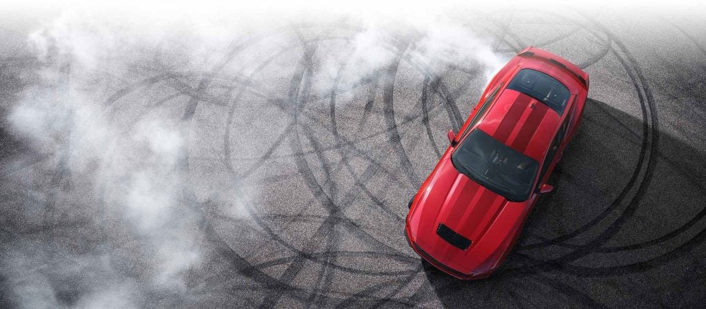Red 2024 Ford Mustang doing donuts in a parking lot 