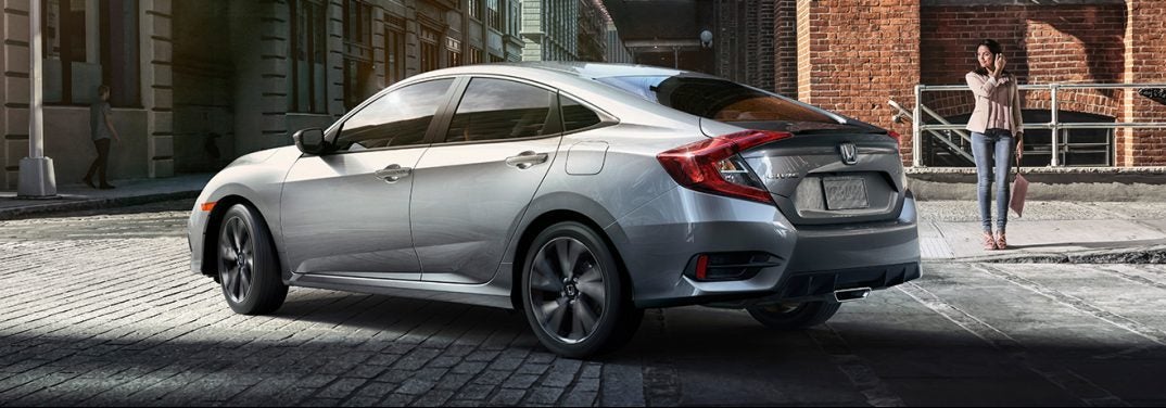 Silver 2019 Honda Civic turns a corner on a cobblestone street.