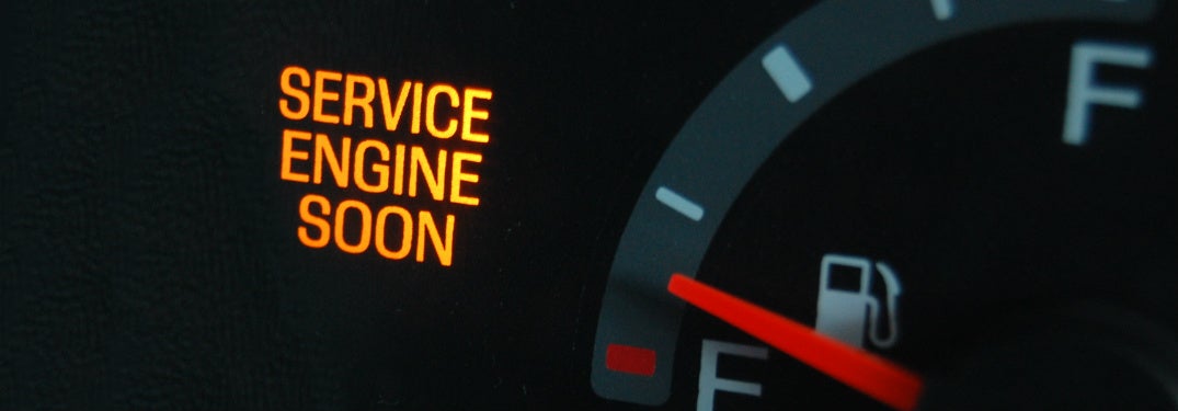 A check engine light on a dashboard is illuminated.