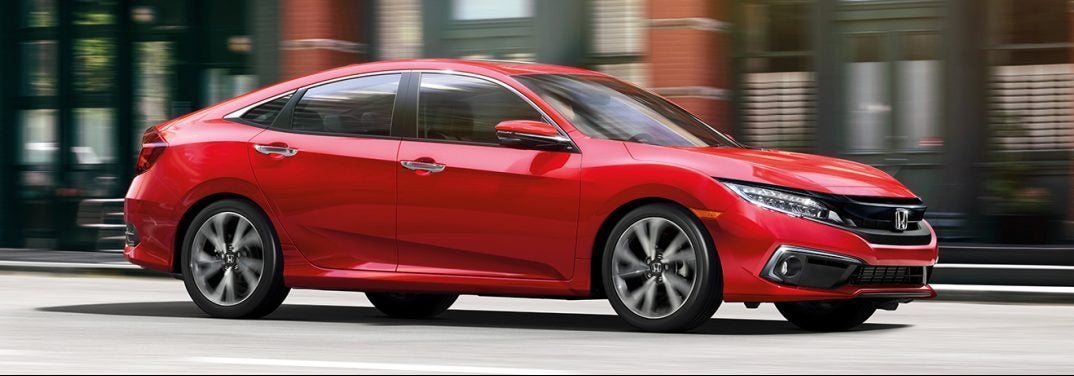 Red 2019 Honda Civic Sedan zooms down a city street.