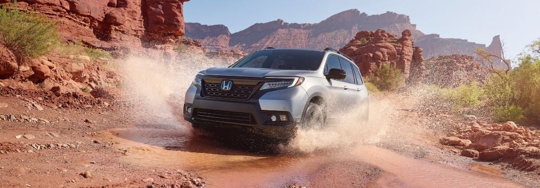 Silver 2021 Honda Passport Splashing Through Mud in a Desert