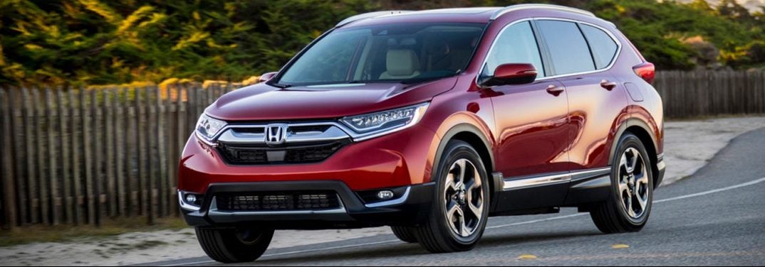 Red 2019 Honda CR-V cruises down a suburban road.