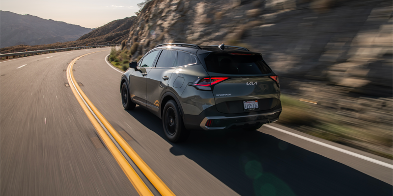 a grey 2025 Kia Sportage driving on a curve of a mountain road