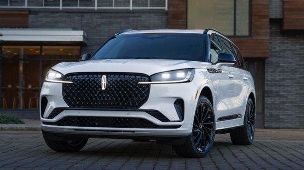 White Lincoln Aviator parked in front of a modern brick building White Lincoln Aviator parked in front of a modern brick building