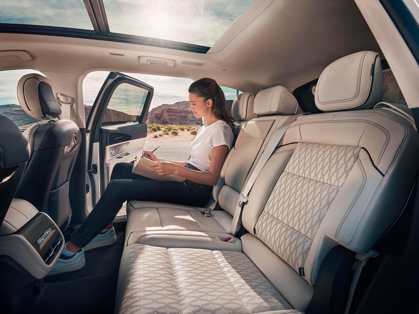 Woman relaxing in the second row of a Lincoln Nautilus with the panoramic roof open Woman relaxing in the second row of a Lincoln Nautilus with the panoramic roof open