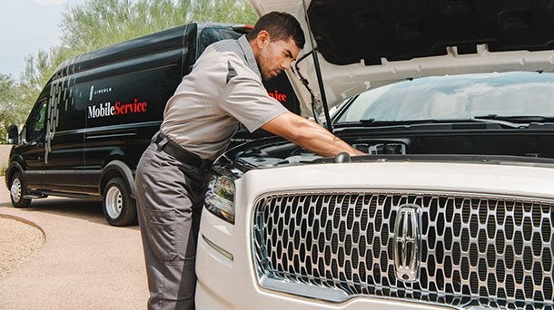 Lincoln service technician checking under the hood of a white Lincoln Navigator