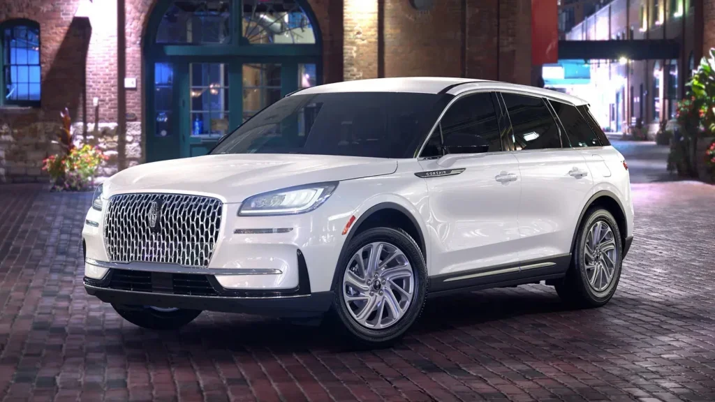 A 2025 Lincoln Corsair® Premiere parked on a cobblestone street at night, illuminated by city lights.