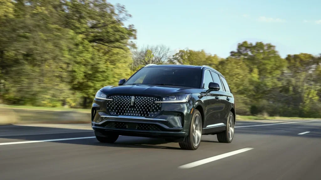 The 2025 Lincoln Black Label Aviator® driving on a forest-lined road.