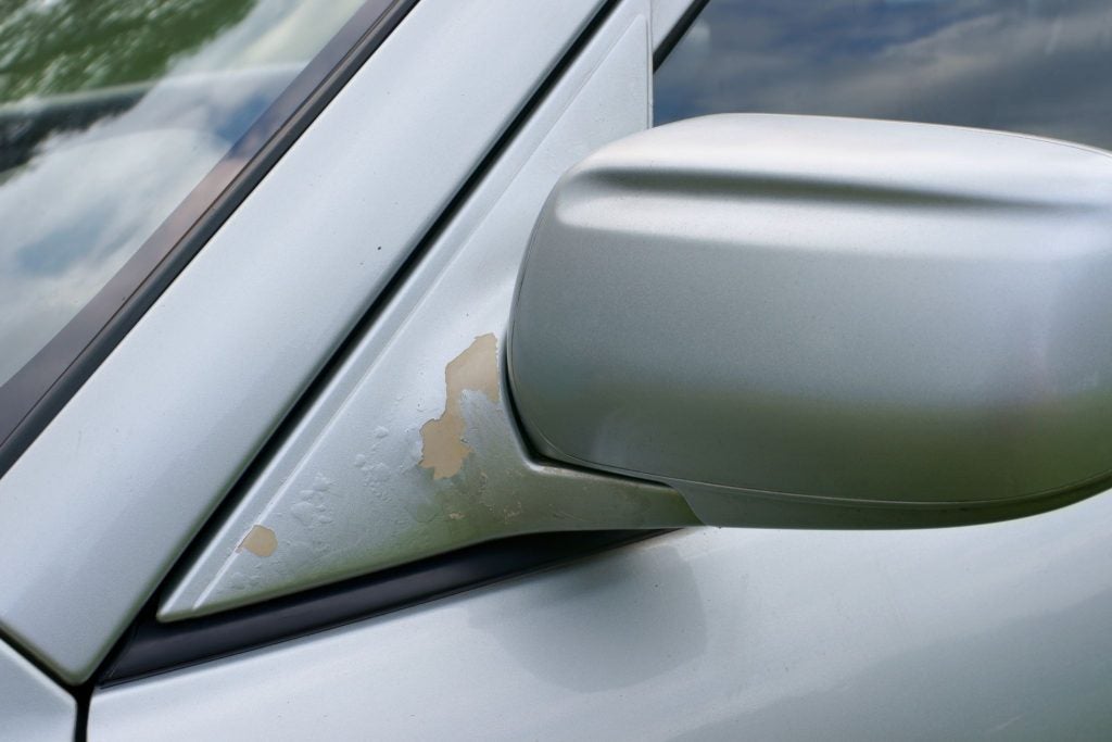 Paint peeling off of the mirror of a car.