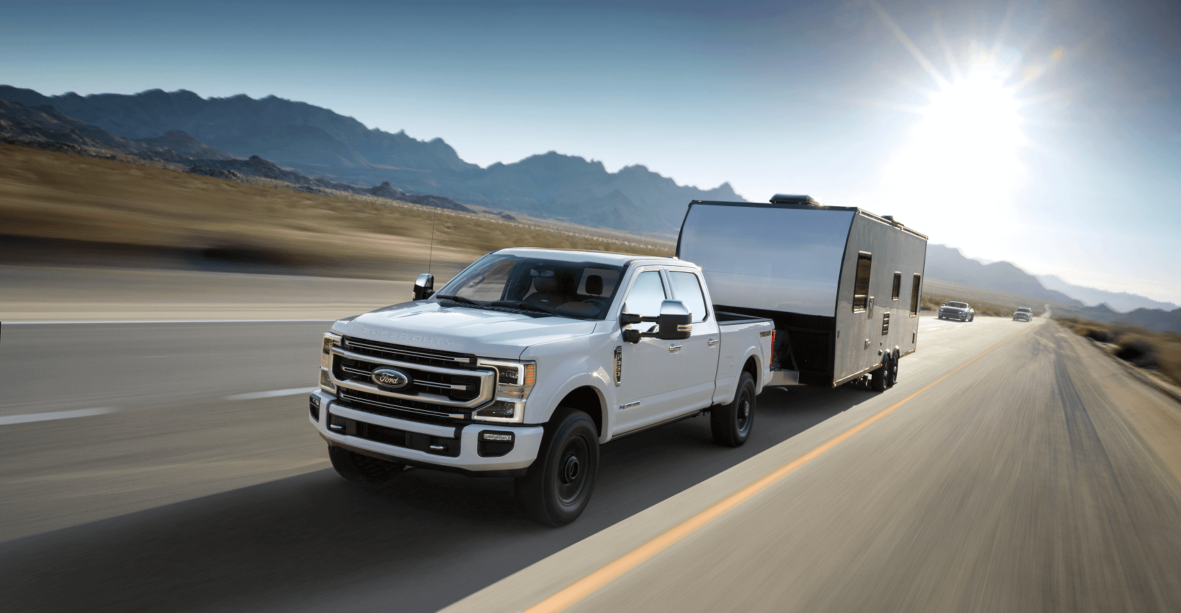 White Ford Super Duty carrying trailer on the road