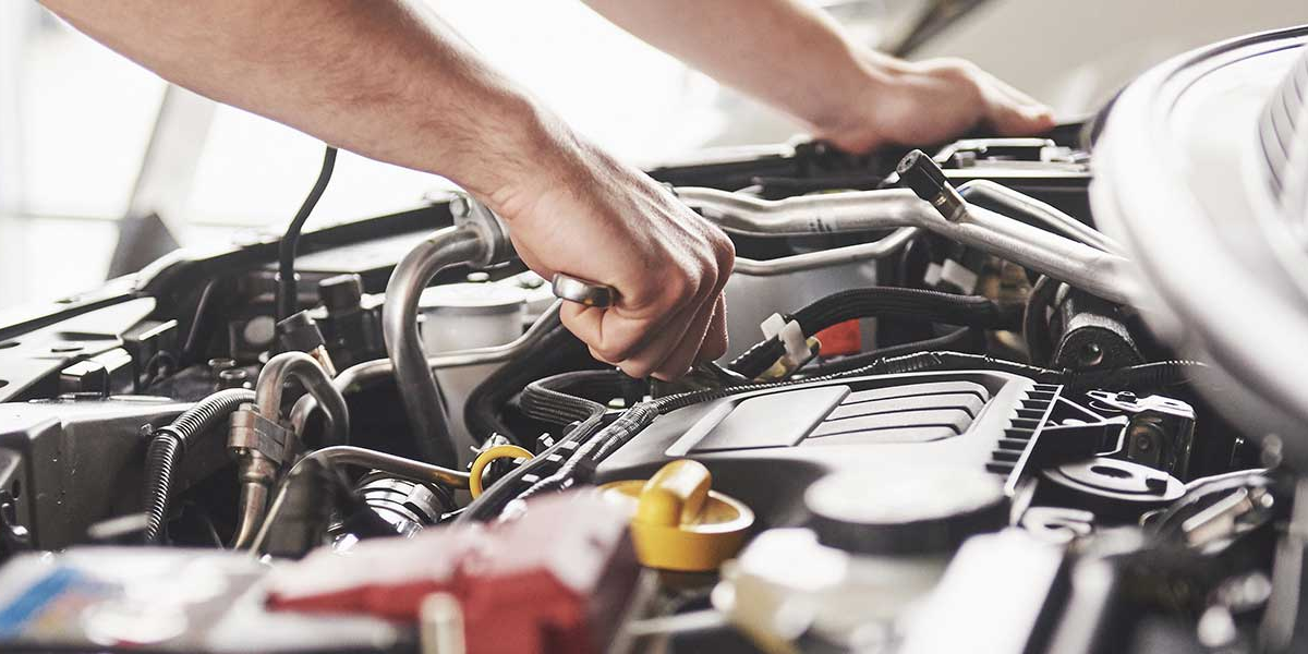A technician working inside the hood of a vehicle