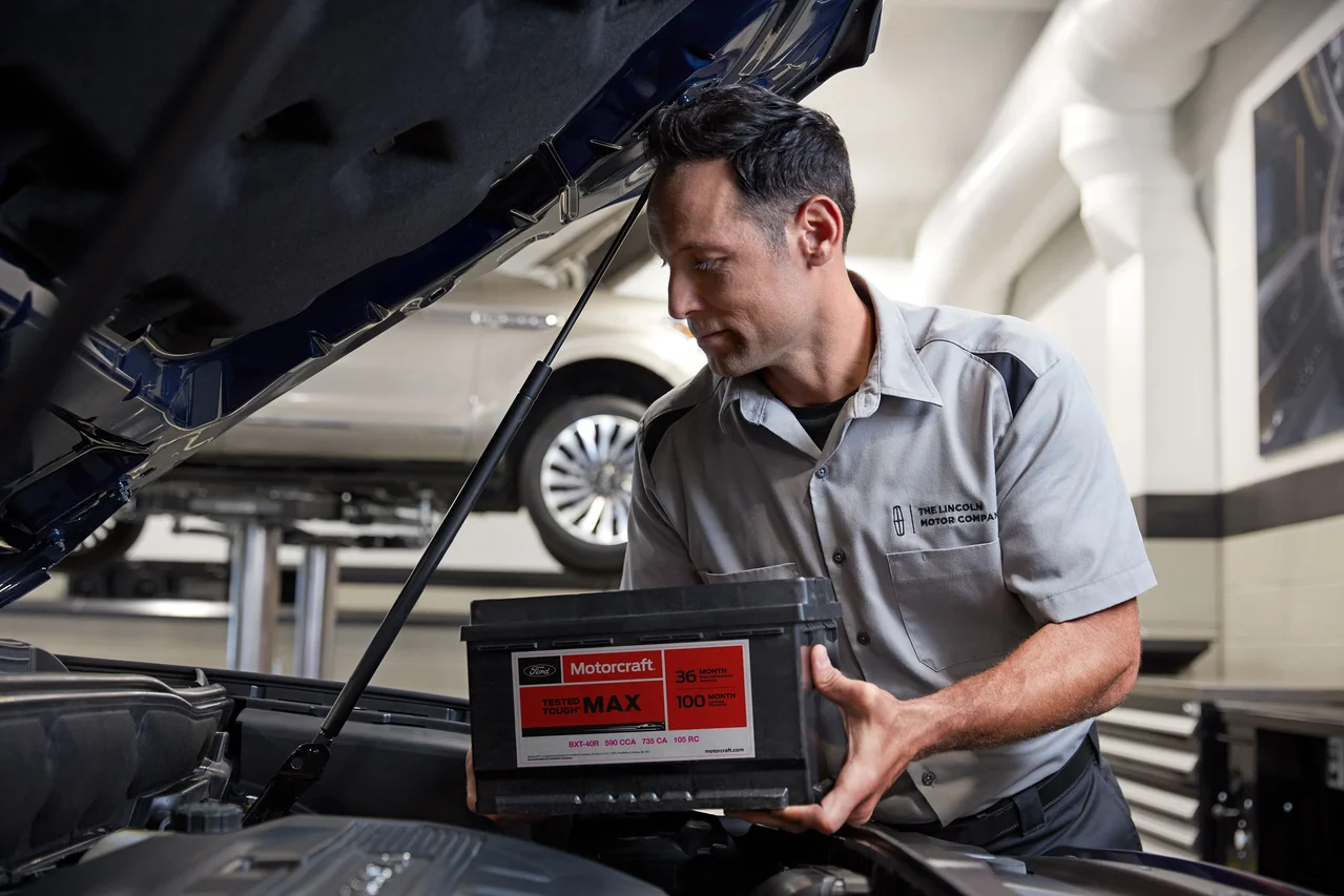 A Lincoln technician handling a car battery