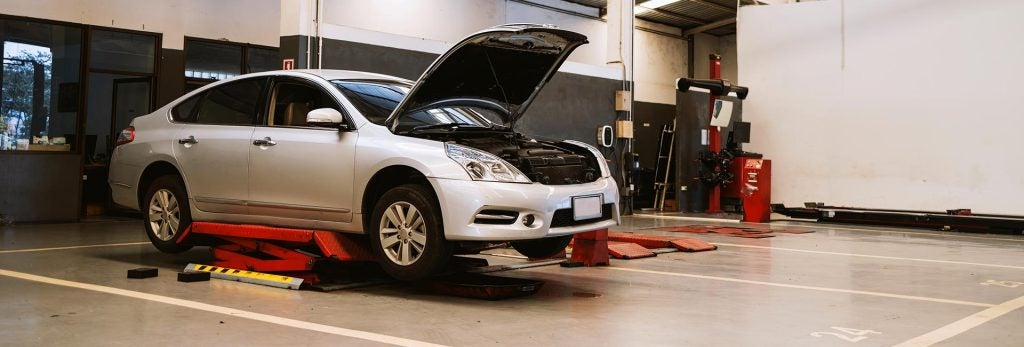 Car on a service lift with hood open.