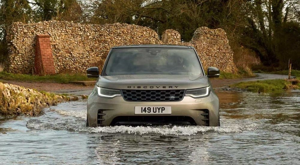 Bronze 2023 Land Rover Discovery driving in the water.