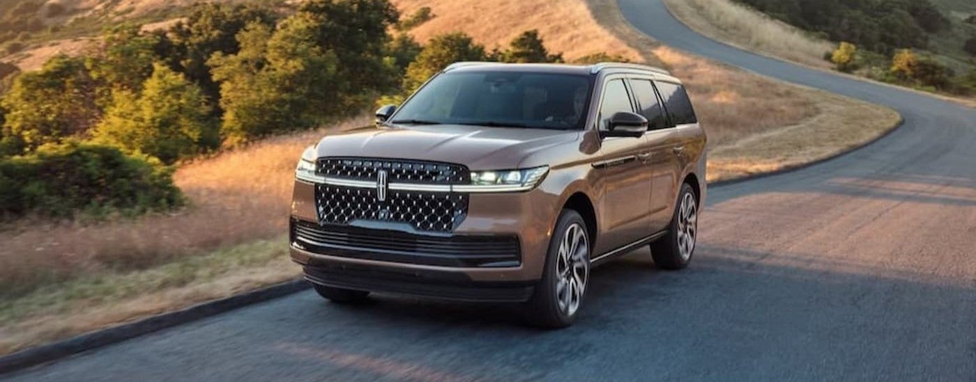 A tan 2026 Lincoln Navigator driving on a highway.