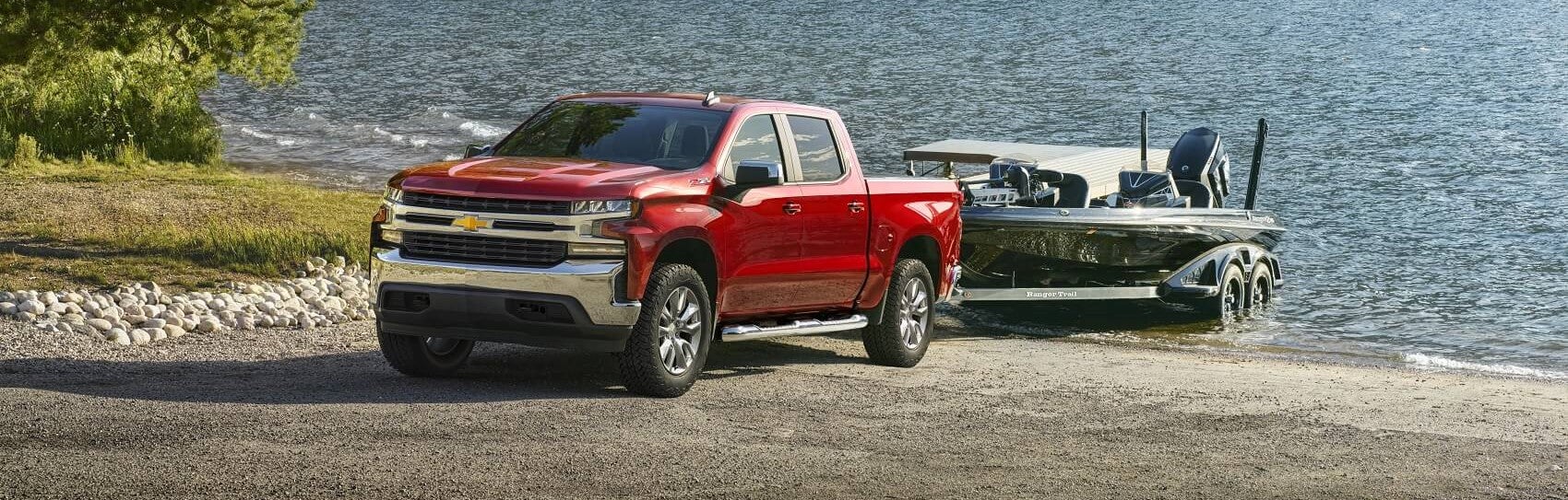 With a towing capacity of 13,000, a red Chevy Silverado easily tows a boat