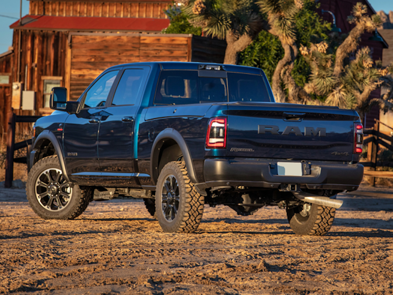 The rear end of a 2024 RAM 2500 in front of a log cabin