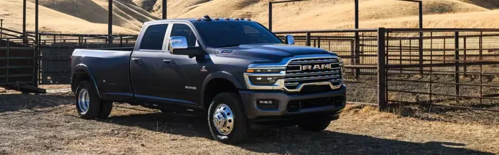 A RAM 2500 Heavy Duty truck parked in a rural area with a metal fence in the background.