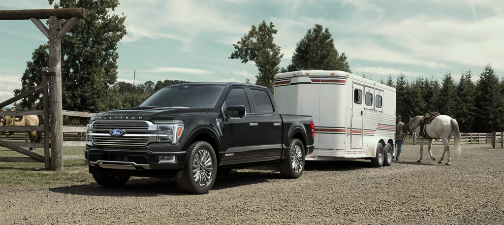 The 2025 Ford F-150 sits parked on a ranch, towing a horse trailer behind it. Find your new 2025 F-150 at Cleveland Ford today.