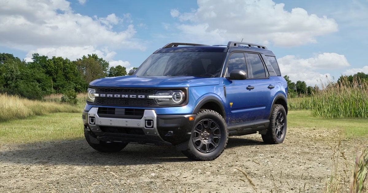 A blue Ford Bronco Sport parked off-road in a field.