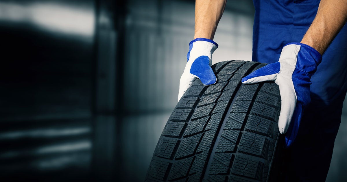 Close-up of a service technician rolling a brand new tire through the service center.