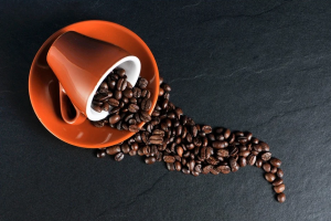 coffee beans spilling out of an orange mug