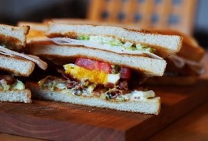 Deli sandwich on a wooden platter.