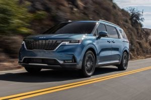 Light blue 2022 Kia Carnival driving on the highway.