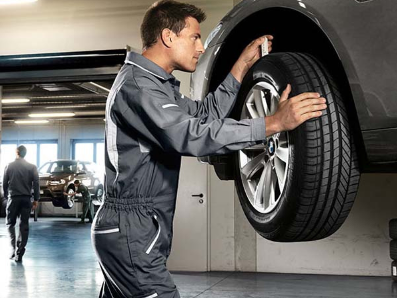 BMW Tire and Wheel Inspection BMW service technician inspecting a tire