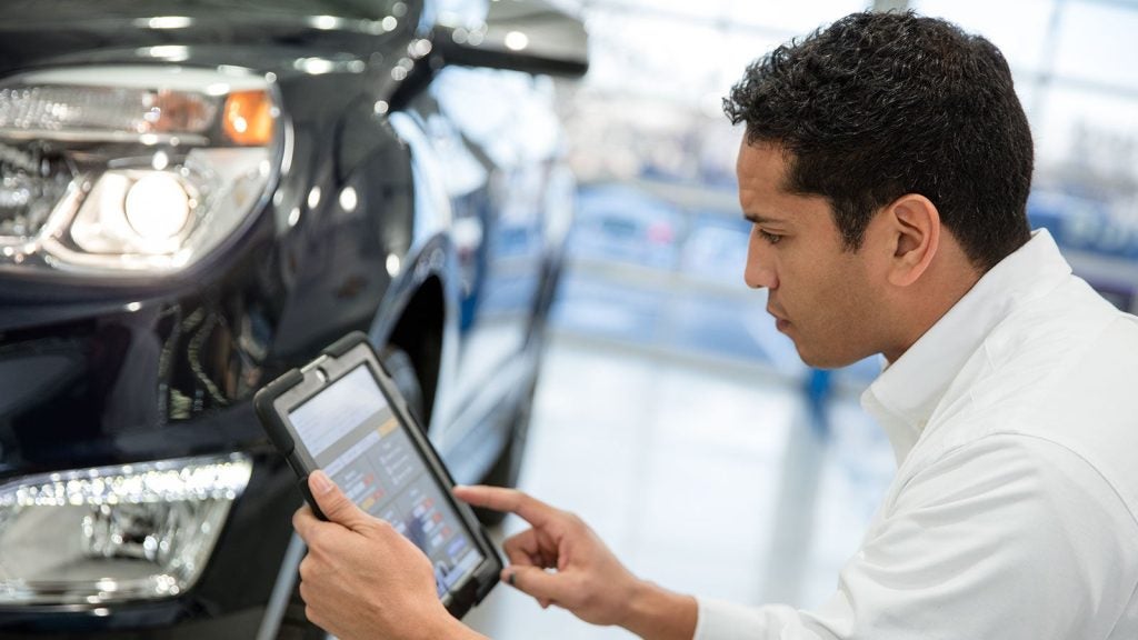 A technician using a tablet to perform a vehicle diagnostic check.