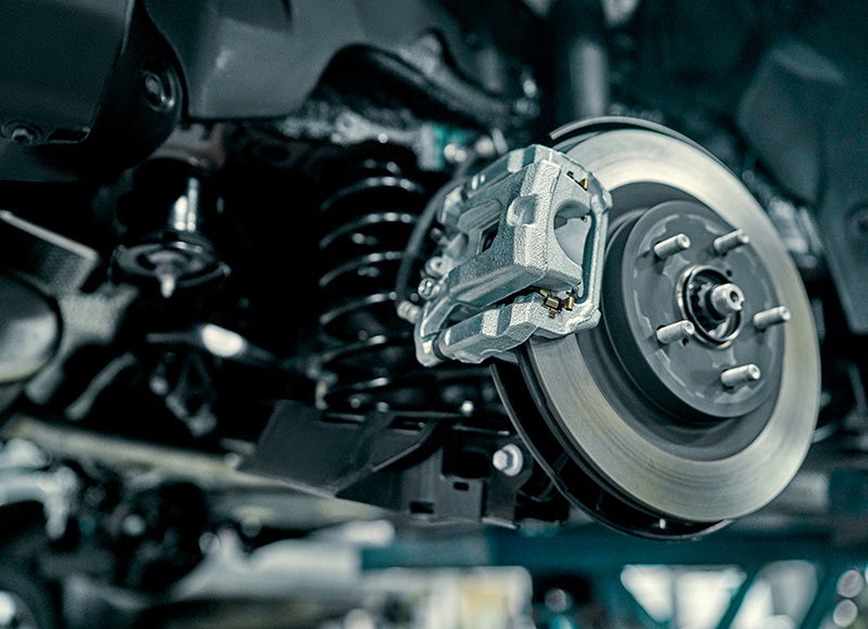 A close-up view of a car's brake rotor, caliper, and suspension assembly.
