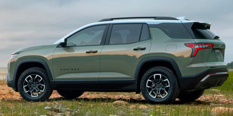 Green Chevrolet Equinox SUV parked on a grassy field with an outdoor landscape in the background.