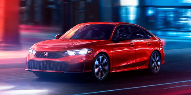 2026 Honda Civic driving on city street at night in red
