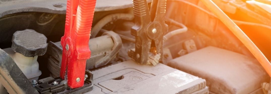 Red and Black Jumper Cables Attached to a Battery at Sunset