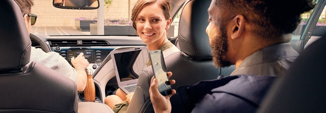 People in a 2020 Toyota Camry Using Smartphones and Toyota Entune Touchscreen