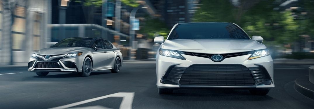 Silver and White 2021 Toyota Camry Models on a City Street at Night