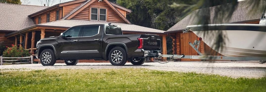 Black 2022 Toyota Tundra Towing a Boat in a Driveway