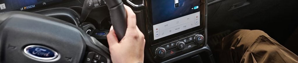 Driver using the Ford steering wheel and touchscreen controls.