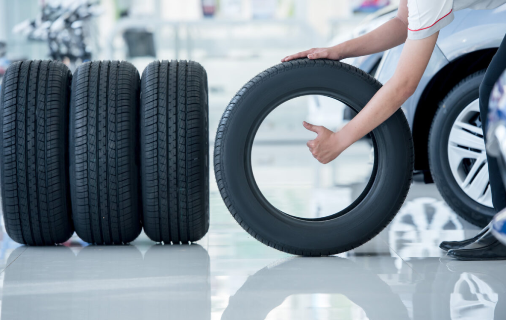 Four car tires and a person giving a thumbs-up.
