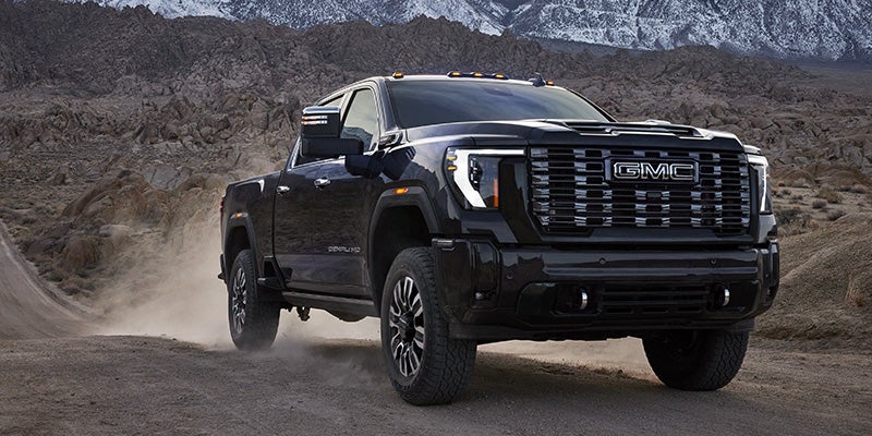 Black GMC Sierra 1500 Denali pickup truck driving through rugged terrain