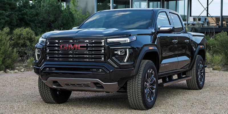 A black GMC Canyon Denali pickup truck, parked outdoors with a rugged, modern design.